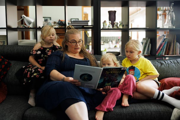 Isabel Weber Bech och hennes tre barn sitter på en soffa och läser en sagobok tillsammans.