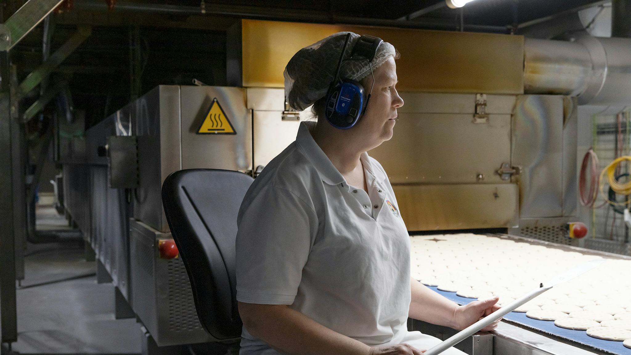 Johanna Öberg kontrollerar brödkakorna innan de med rasande fart åker in i ugnen på Polarbröds nya bageri i Älvsbyn. Redan på hösten 2021, drygt ett år efter den förödande branden, var hon tillbaka på jobbet i bageriet.