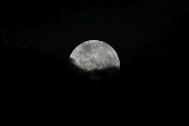En måne syns på mörk himmel