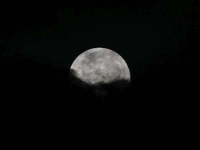 En måne syns på mörk himmel