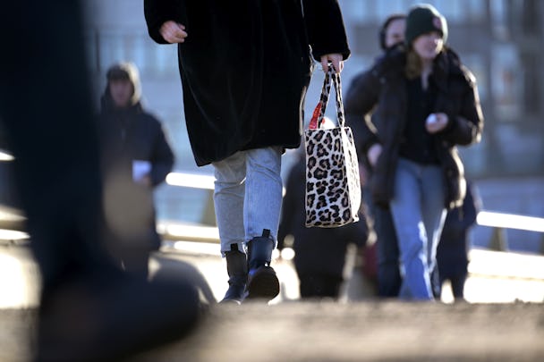 En kvinna som går nerför en gata med en väska.