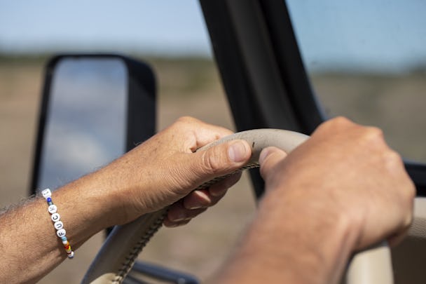 En man som kör bil med ett armband på handleden.