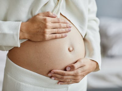 En gravid kvinna med händerna på magen.