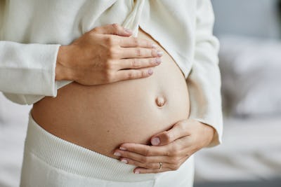 En gravid kvinna med händerna på magen.