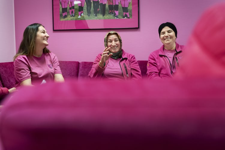 Städarna Elife Demirci, Zeliha Bulduk och Gülüzar Atik sitter tillsammans i en soffa och skrattar.