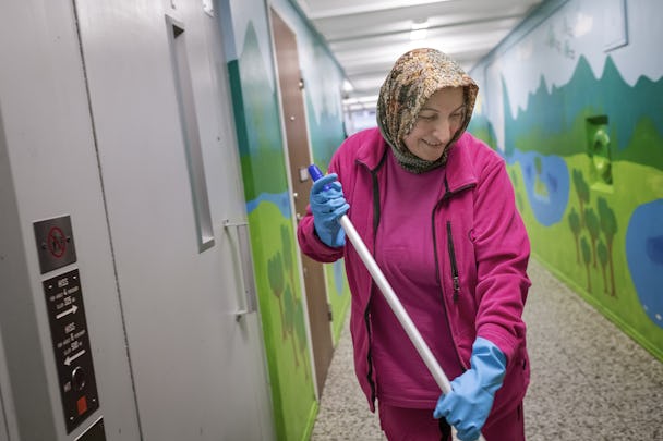 Zeliha Bulduk har arbetskläder och moppar i en korridor. Hon ser glad ut.