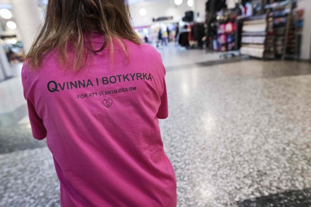 Bild på en kvinnas rygg tavla. På den rosa tröjan står ”Qvinna i Botkyrka – för att vi bryr oss om”.
