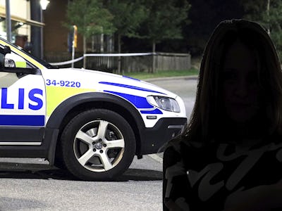 En kvinna står framför en polisbil.