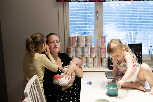 Jennifer Blomberg håller sin yngsta son Benjamin i köket. Två andra barn viskar i hennes öra och klättrar på bordet.