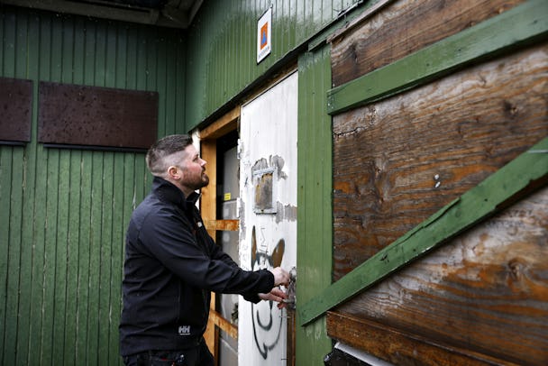 Johan Söderberg känner på en vit dörr med en skyddsrumsskylt ovanför.