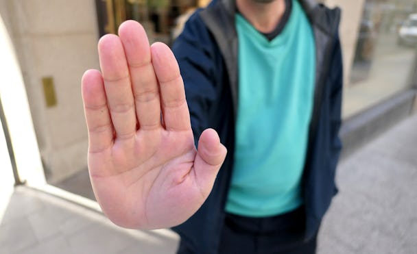 Man som håller upp en nekande hand utanför en butik.