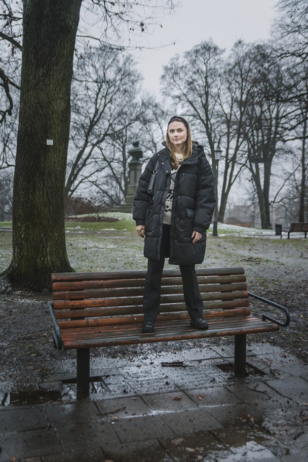 Låtskrivaren Tilde Wrigsell (artistnamn Ronia) står på en parkbänk i grått väder.