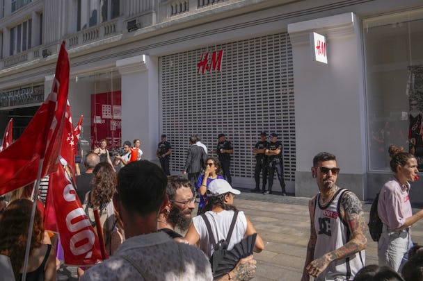 Strejkande H&M-anställda protesterar framför en stängd H&M-butik I Madrid.
