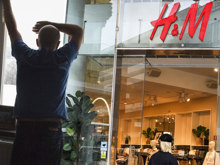 En man lutar sig ut genom fönstret och en H&M butik.