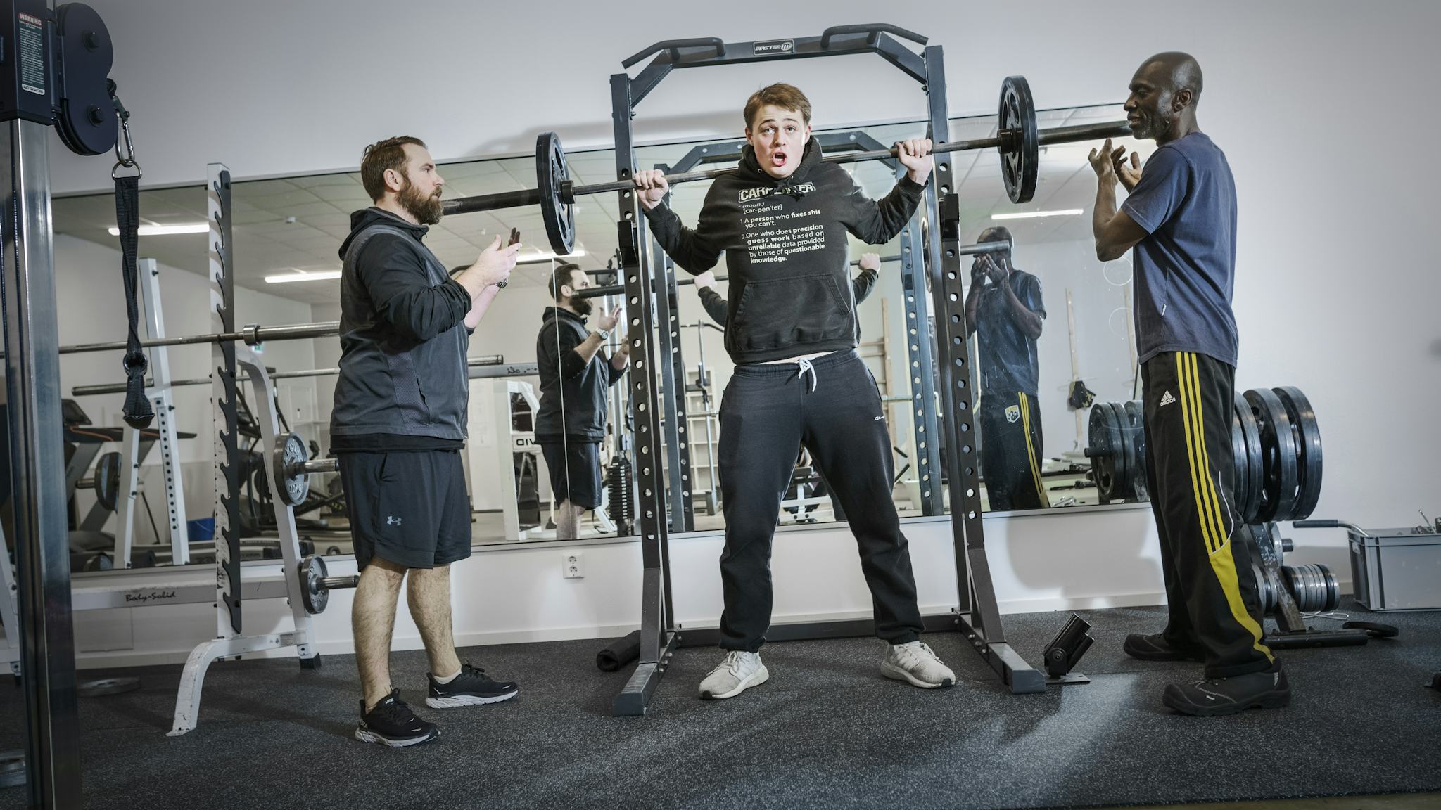 Tre män tränar på ett gym.