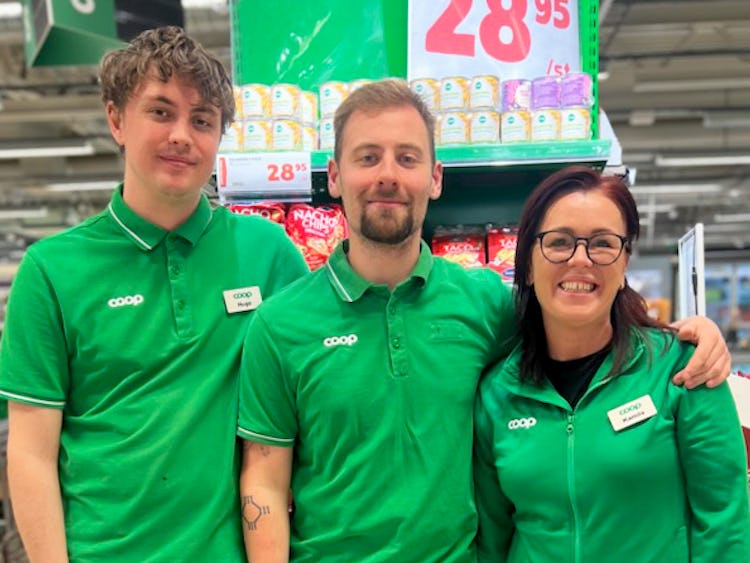 Tre personer i gröna skjortor som står bredvid varandra i en Coop-butik.