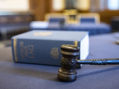 En klubba och en juridisk kodbok på ett bord inne i en rättssal.