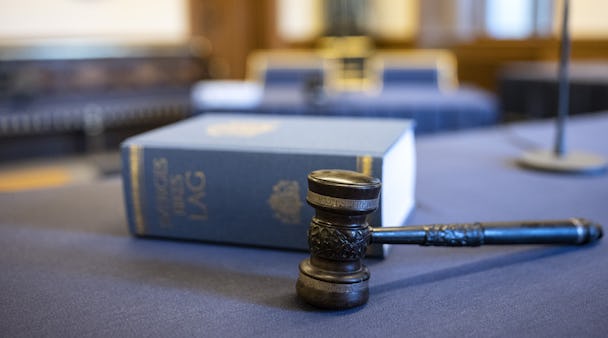 En klubba och en juridisk kodbok på ett bord inne i en rättssal.