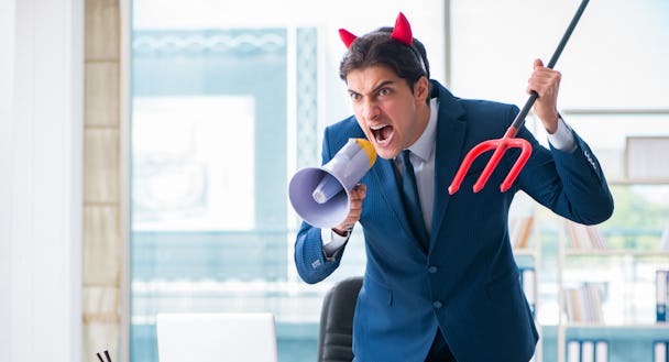 En affärsman med djävulshorn som skriker vid ett skrivbord.