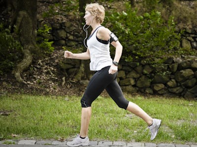 En kvinna som joggar i en park med hörlurar.