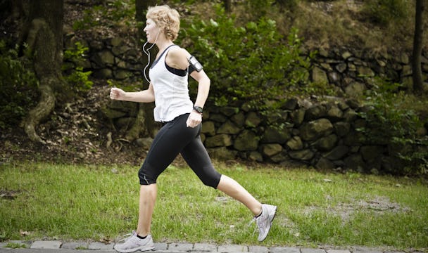 En kvinna som joggar i en park med hörlurar.