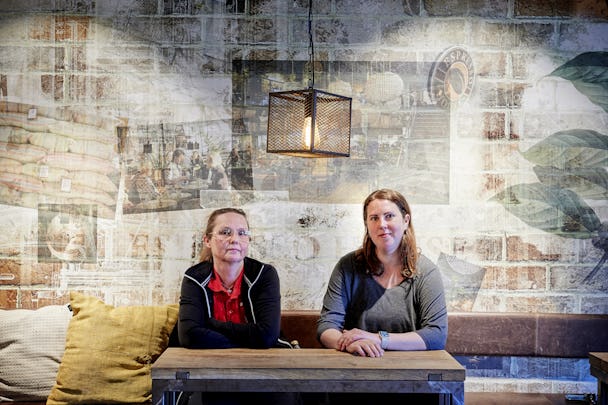 Två kvinnor sitter vid ett träbord i ett café.