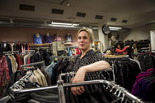 En person står bland klädställningar i en butik och tittar på kameran.