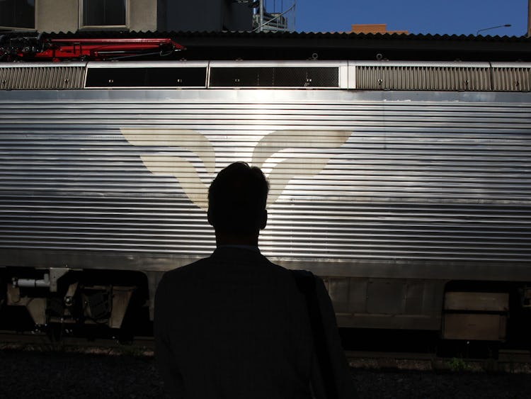 En person i siluett står framför en tågvagn med SJ:s logotyp på.