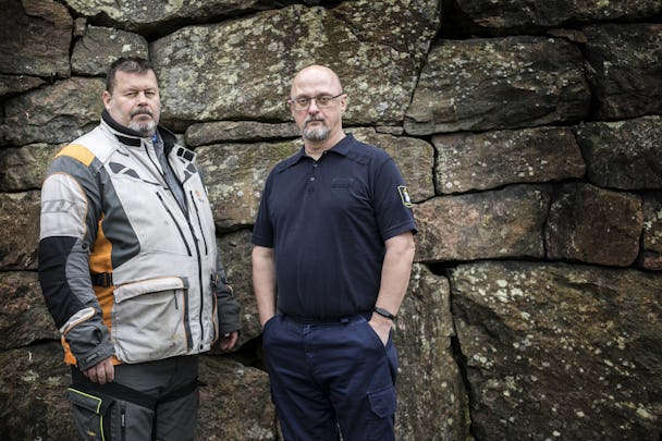 Halv kroppsbild på två män, er Simonsson och Stefan Römer, framför en stenmur.