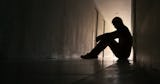 Person i siluett sitter ensam på ett golv i en mörk korridor.