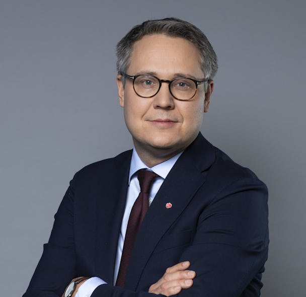 Biträdande arbetsmarknadsminister Johan Danielsson (S) i kostym mot grå bakgrund.