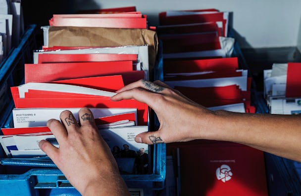 Postnords brevbärare Emilia Leijon-Amréns händer i närbild när de sorterar post.