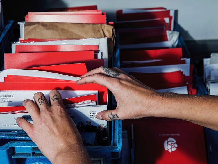Postnords brevbärare Emilia Leijon-Amréns händer i närbild när de sorterar post.
