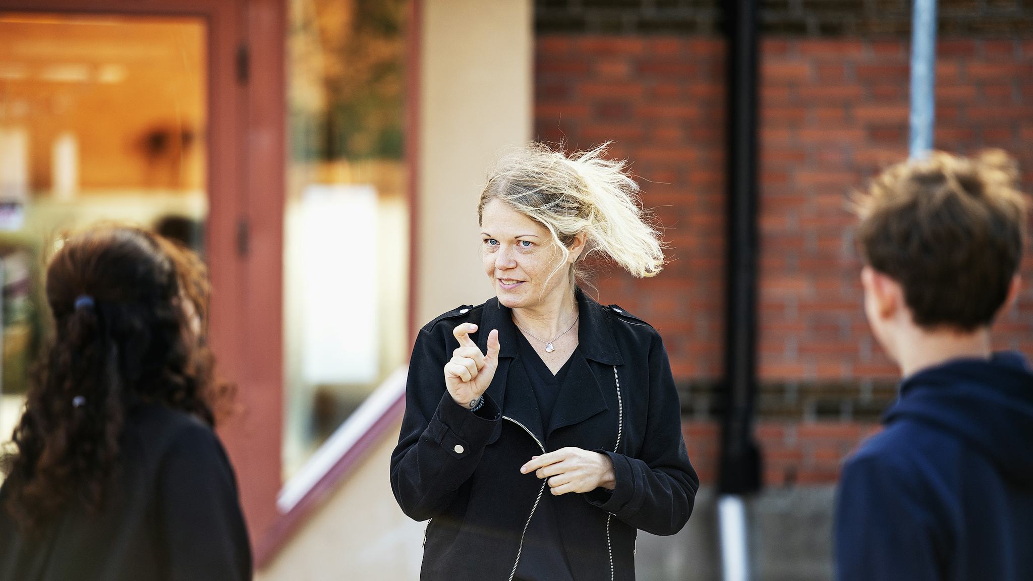 Zara Strömstedt använder teckenspråk när hon kommunicerar med två elever på Vänerskolans skolgård.