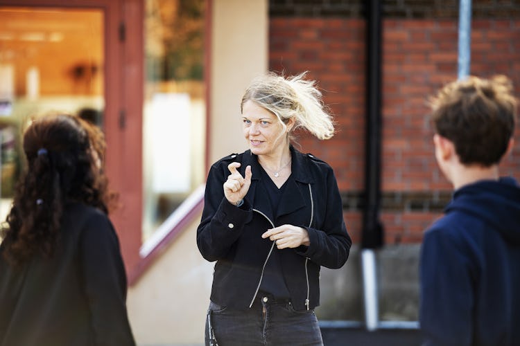 Zara Strömstedt använder teckenspråk när hon kommunicerar med två elever på Vänerskolans skolgård.