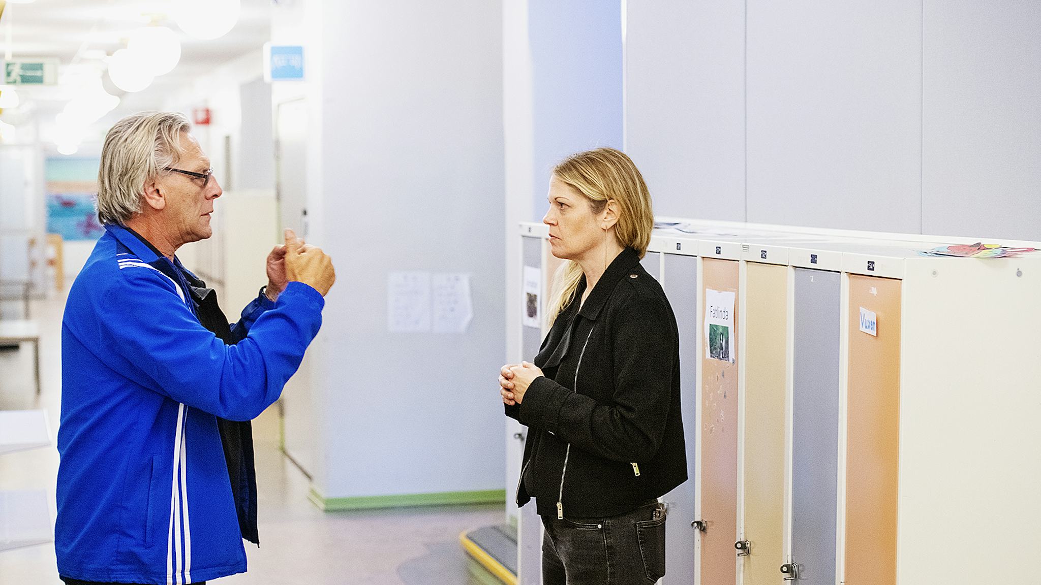 Zara Strömstedt läser av Ulf Hansons teckenspråk i korridoren på Vänerskolan. Bakom Zaras rygg är en rad med skåp.