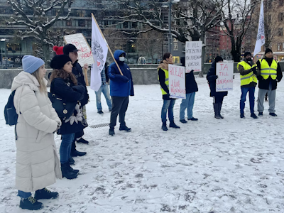 Personer demonstrerar utanför LO-borgen i ett vintrigt Stockholm. De håller skyltar med krav på högre löner.