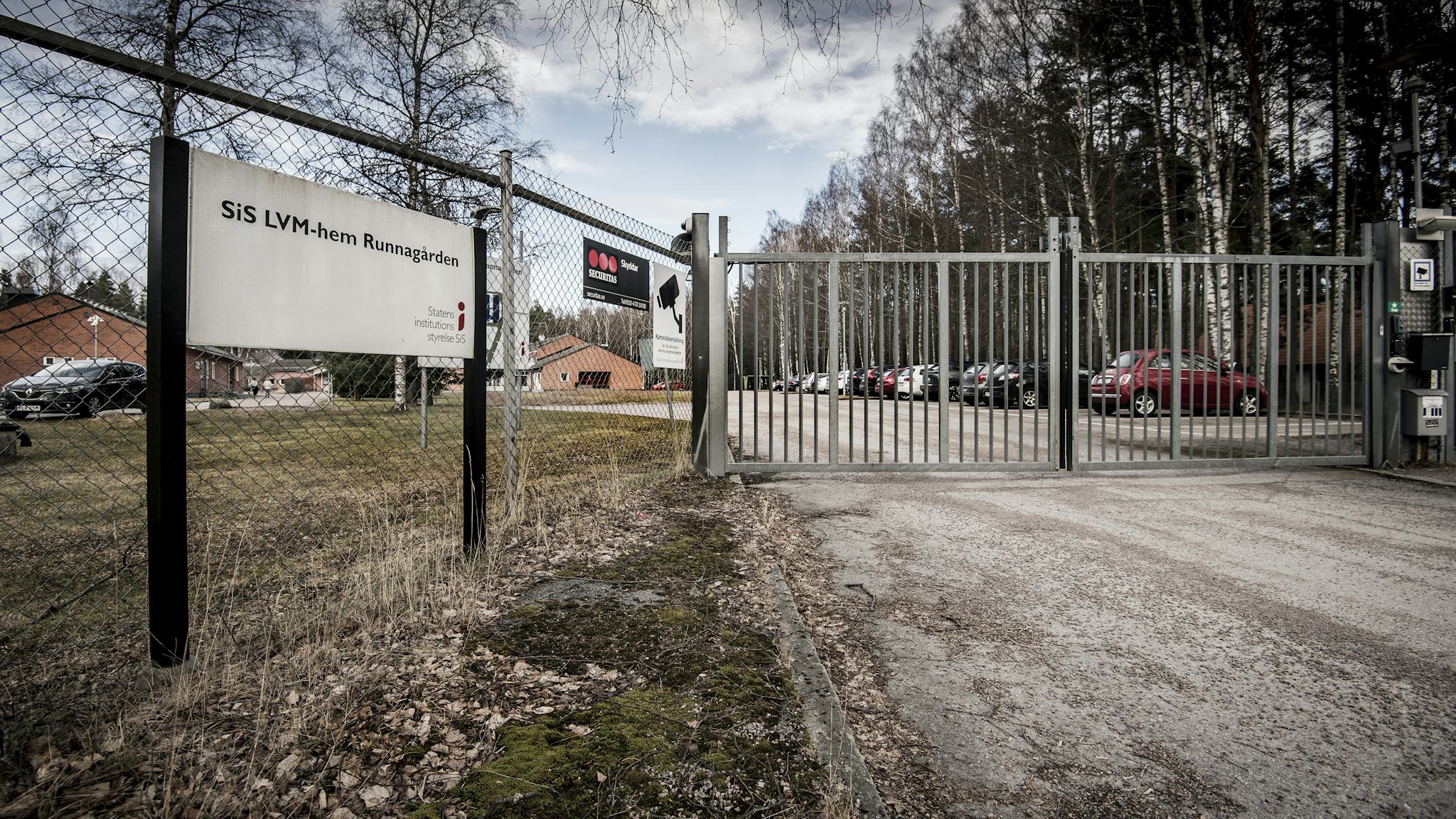 Ingången till det inhägnade området för LVM-hemmet Runnagården. Skyltar visar att området är kameranbevakat och stora grindar är låsta vid inkörsvägen.