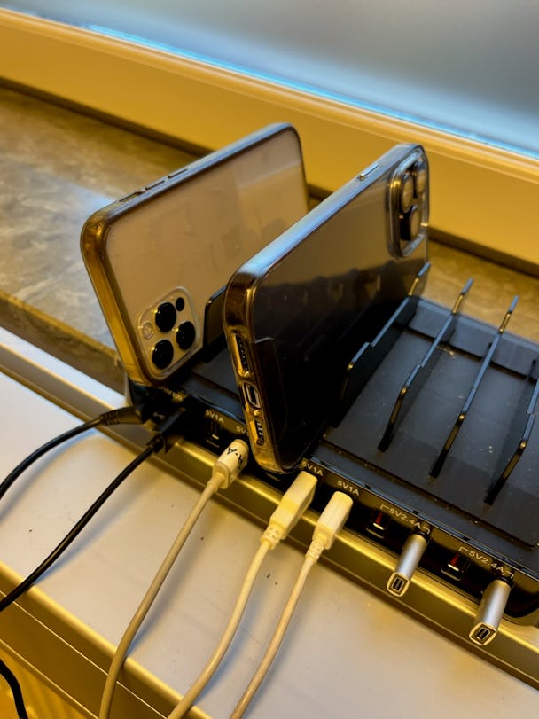 Närbild på två mobiltelefoner som ligger på laddning i en ladningsstation.