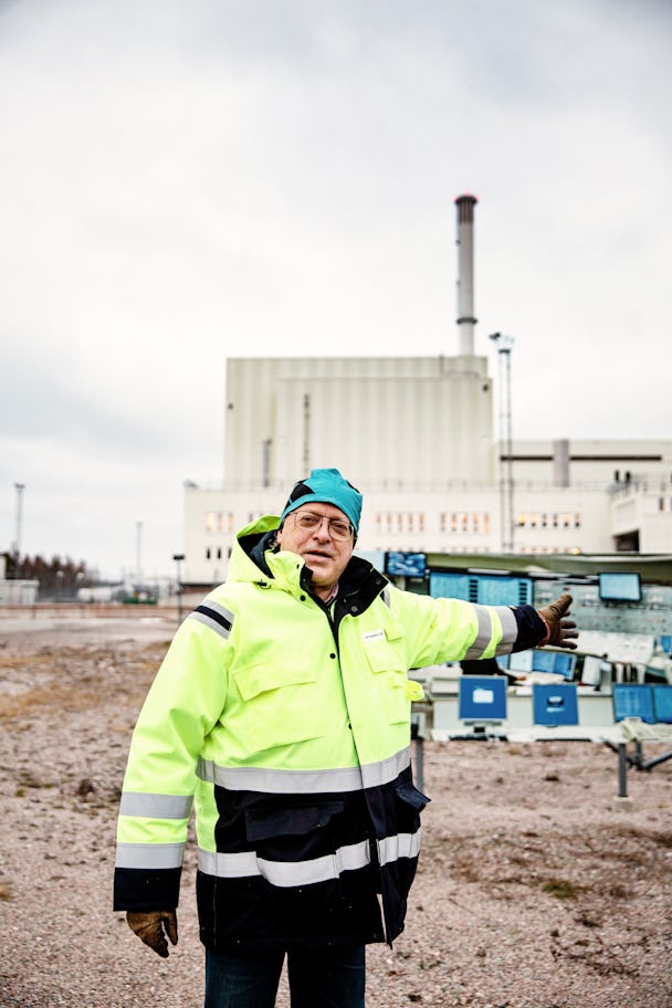 Processingenjören Ingemar Eriksson framför reaktor 3 vid Formarks kärnkraftverk. Han är klädd i en gul varseljacka och pekar på kärnkraftverket samt reklamskyltar som visar hur det ser ut inuti kontrollrummet.