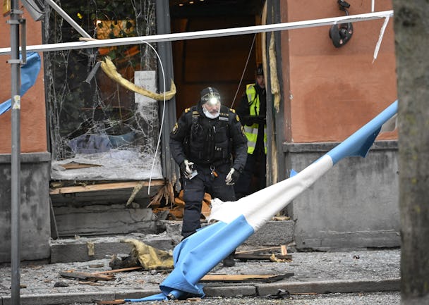 En polis undersöker resterna av en sprängd entré på Södermalm i Stockholm.