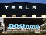 Delad bild på fasad där det står ”Tesla” och ”Postnord”-text utanför Postnords huvudkontor.