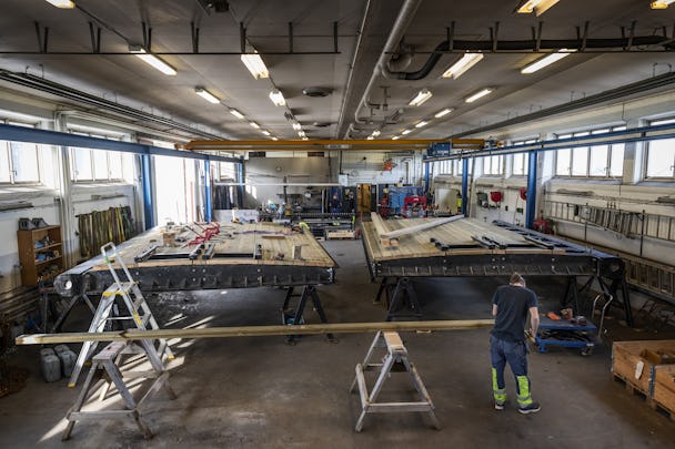 Interiör från verkstaden i Berg. En arbetare jobbar med en planka och två slussportar syns i bakgrunden.