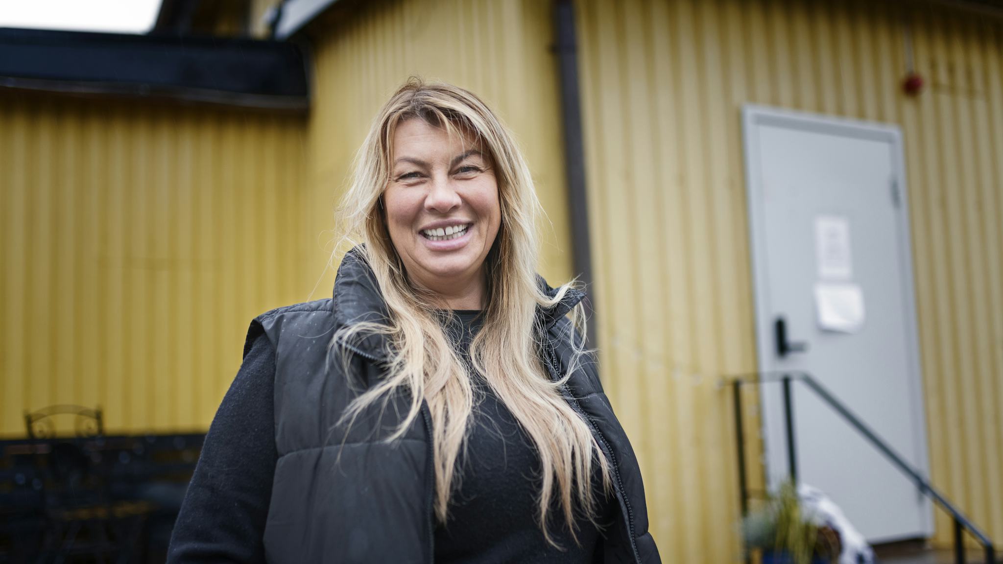 Malin Enström ler framför den gula byggnaden Ladan.