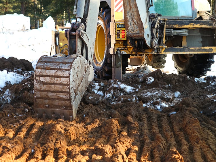 En arbetsmaskin gräver ett hål i snön.