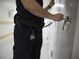 En man i uniform öppnar en dörr på ett häkte.