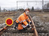 Kenneth Nilsson i hjälm och orange arbetskläder arbetar med utrustning vid ett järnvägsspår.
