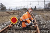 Kenneth Nilsson i hjälm och orange arbetskläder arbetar med utrustning vid ett järnvägsspår.