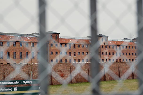 En vy av en fängelsebyggnad i tegel bakom ett stängsel.