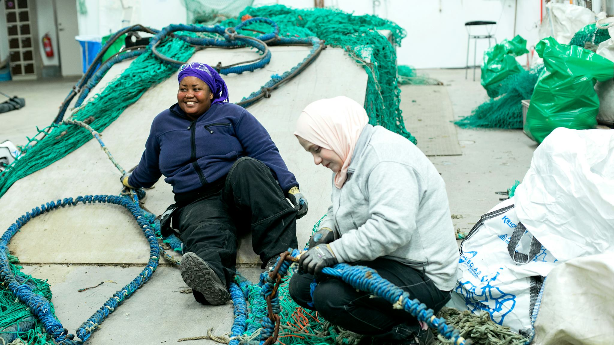 Djamila Moustapha och Waad Almallouhi rensar uttjänta fiskelinor från schackel och kättingar.